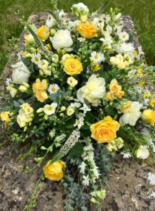 Coffin spray of yellow and white country flowers